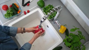 Lavabonun üzerinde kırmızı biber yıkayan bir kadının manzarası