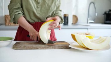 Woman Cutting Melon Into Pieces In The Kitchen Close-Up