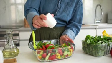 Woman Adding Salt To Vegetable Salad Of Tomatoes, Peppers, Greens