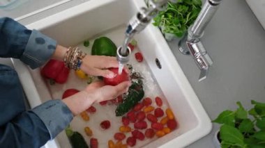 Lavabonun üzerinde kırmızı biber yıkayan bir kadının manzarası