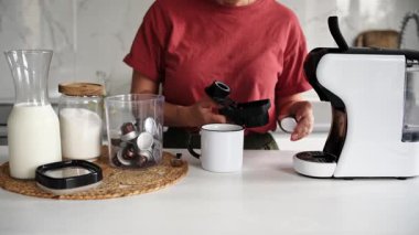 Mutfakta kahve makinesinde kahve yapan bir kadın.