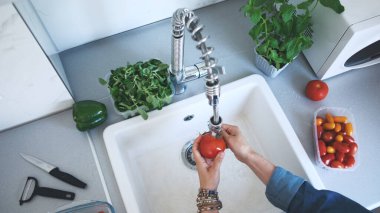 View From Above Of A Woman Washing Tomato Over Sink