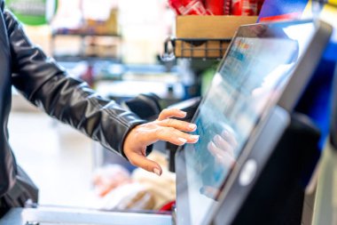 Kadın süpermarkette kişisel servis kontrolünde monitöre basıyor.