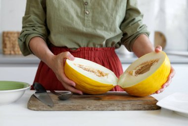Woman Cutting Melon In Half In Close-Up Kitchen Scene