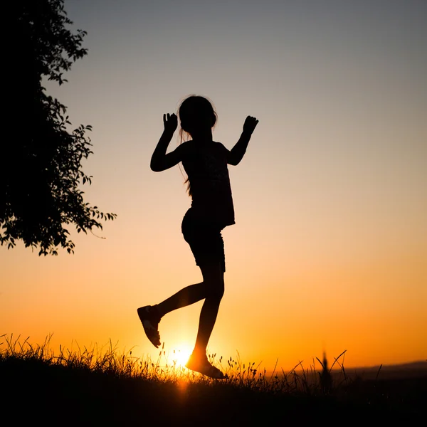 Tiener meisje in de ondergaande zon — Stockfoto