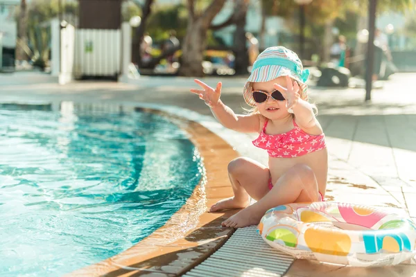 小さな女の子が、プールのそばに座って — ストック写真