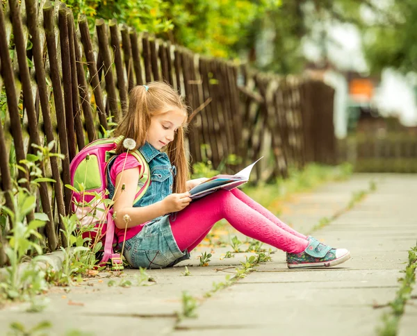 Schoolmeisje lezen van een boek op straat — Stockfoto