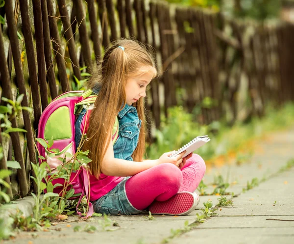 Schoolgirl reading  book  on street — Stock Photo, Image