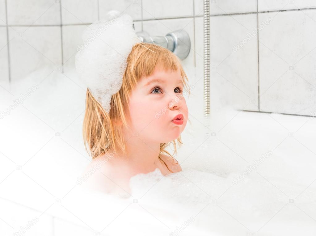 cute baby bathes in  bath with foam