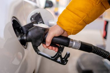 Yakından çekilen bir elle arabaya yakıt ikmali yapılıyor.