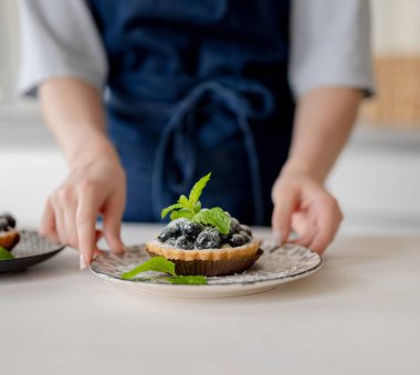 Mutfakta elinde yaban mersinli tatlı tutan kız.