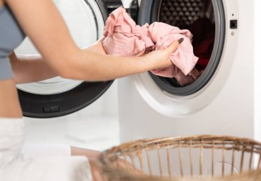 Çamaşır sepetinden çamaşır makinesine çamaşır koyan bir kadının yakın çekimi