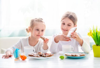 Mutfakta Paskalya kurabiyeleriyle çay içen iki kız.