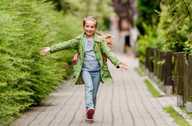 Sırt çantasıyla okula koşan mutlu kız