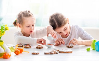 Paskalya için zencefilli kurabiye süsleyen iki küçük kız