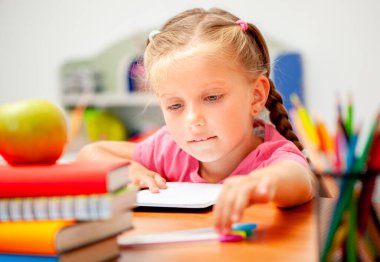 Evde ödev yaparken kalem arayan bir kız.