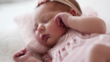 Yeni doğan bebek fotoğraf çekilirken dantelli elbise giyer.