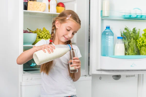 Маленька дівчинка вливає молоко в склянку — стокове фото
