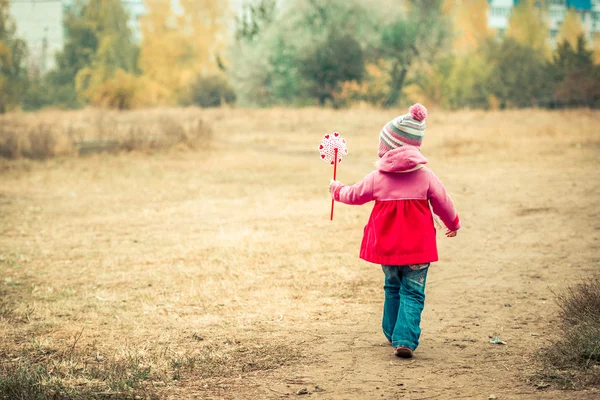 Liten flicka gå med väderkvarn — Stockfoto