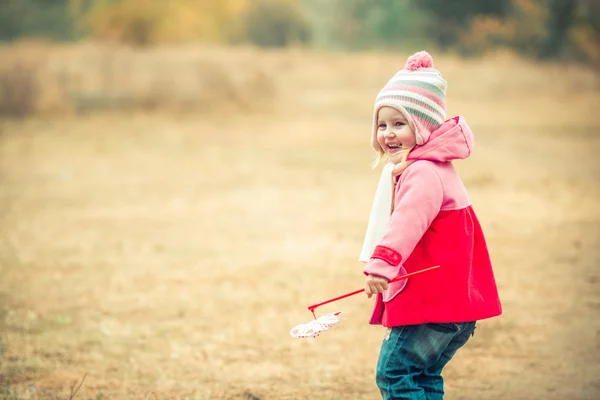 Pequena menina sorridente na paisagem do outono — Fotografia de Stock