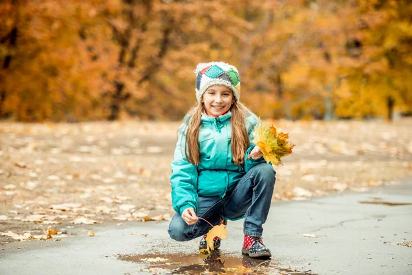 Little girl squatting with leaves — 스톡 사진