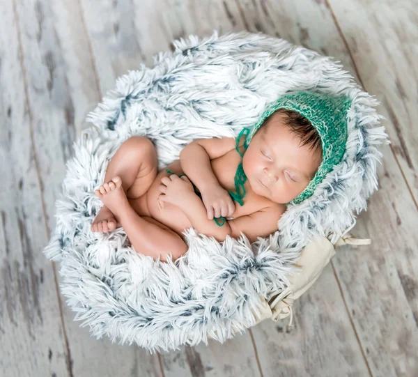 Bebê recém-nascido com chapéu verde dormindo em uma cesta — Fotografia de Stock