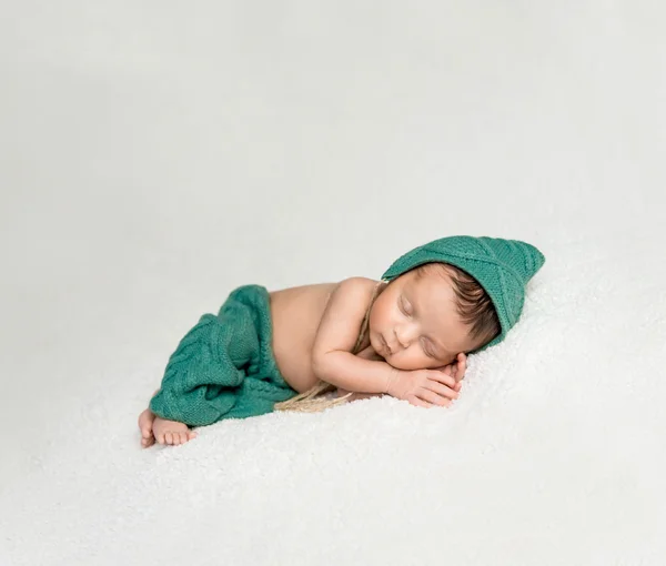 Newborn boy in green suit sleeping on blanket — Stock Photo, Image