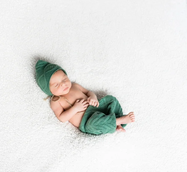 Newborn boy in green suit sleeping on blanket — Stock Photo, Image