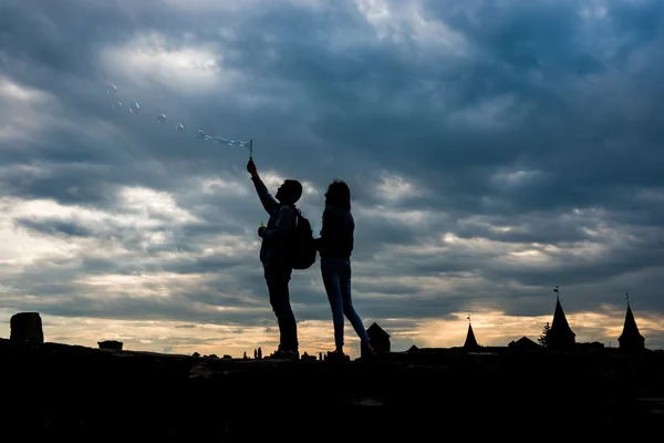 Joven pareja soplar burbujas en la puesta del sol — Foto de Stock
