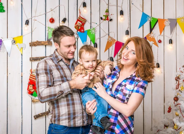 Familia joven en sombreros rojos con hijo pequeño cerca del árbol de Navidad — Foto de Stock