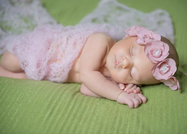 Pasgeboren baby met bloem krans slapen op een deken — Stockfoto