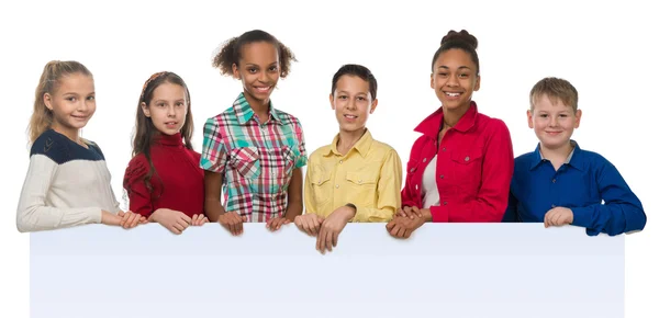 Niños de diferente tez sosteniendo un vacío en blanco con los pulgares hacia arriba — Foto de Stock