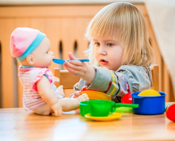 Menina alimentando uma boneca — Fotografia de Stock