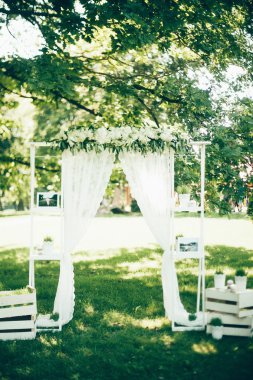 Düğün kemeri, kumaş çiçekler ve yeşillikle süslenmiş.