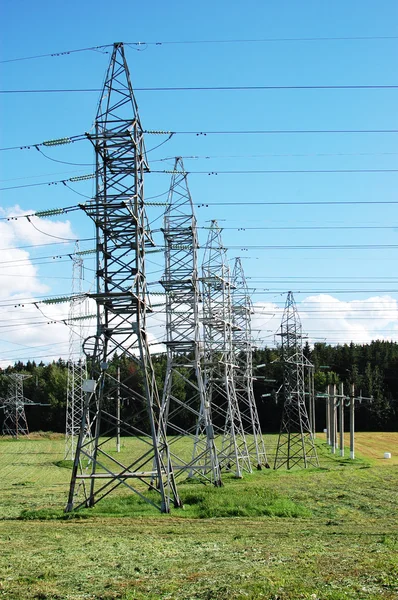 Central eléctrica en el campo en el cielo azul nublado. Líneas de alta tensión y torres eléctricas en un paisaje agrícola plano y verde en un día soleado con nubes de cirros en el cielo azul — Foto de Stock