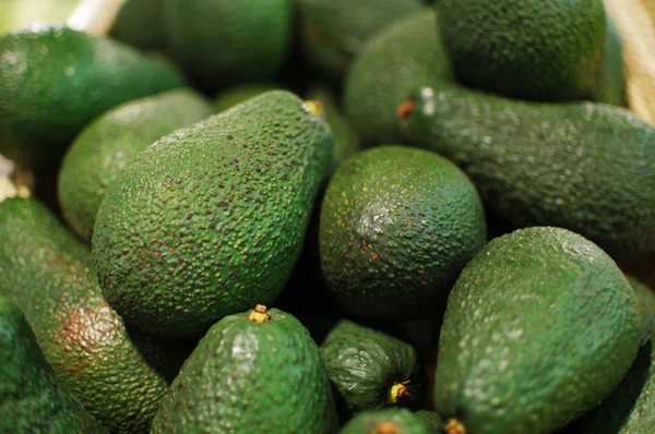 Un mucchio di avocado verdi nel cestino del mercato. Avocado da vicino — Foto Stock