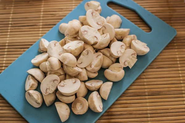 Slicing mushrooms on a cutting blue board — Stock Photo, Image