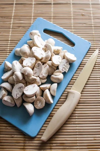 Slicing mushrooms on a cutting blue board — Stock Photo, Image