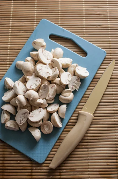 Slicing mushrooms on a cutting blue board — Stock Photo, Image