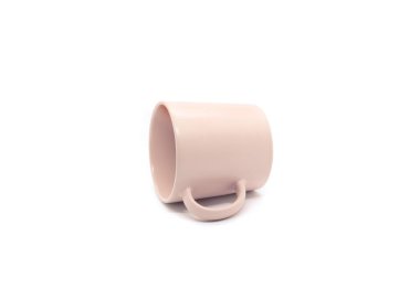 Boş açık pembe seramik bardak yan yatar beyaz arka planda izole