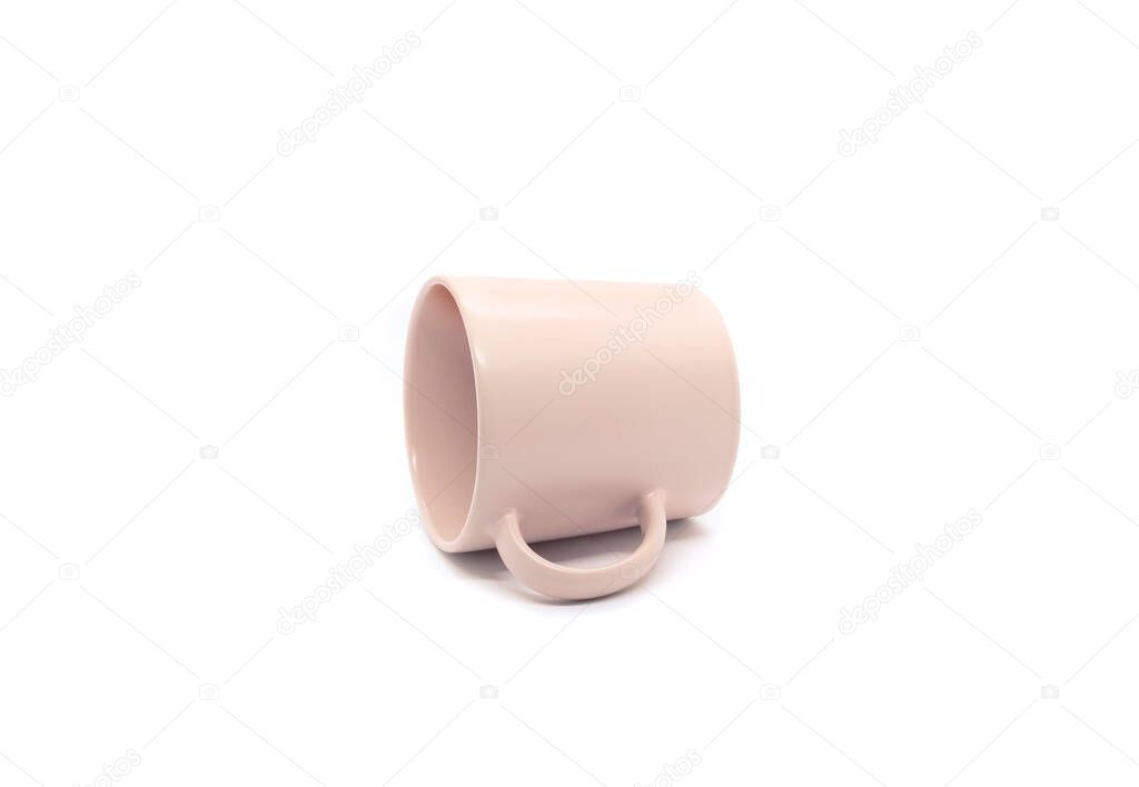 Empty light pink ceramic mug lying on its side isolated on white background