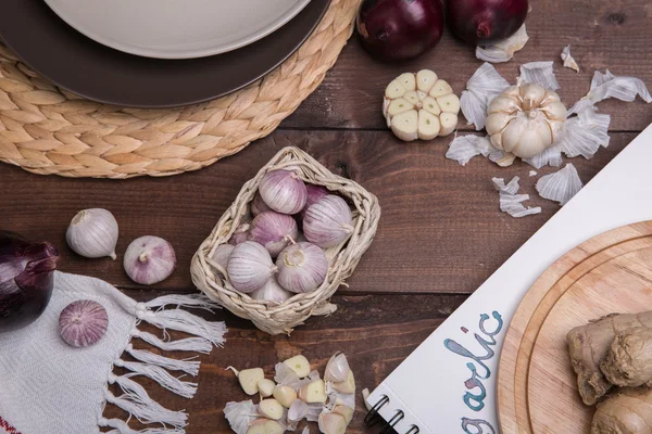 Garlic on a wooden table with utensils — Stock Photo, Image