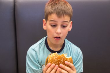 Sevimli çocuk hamburger yiyor