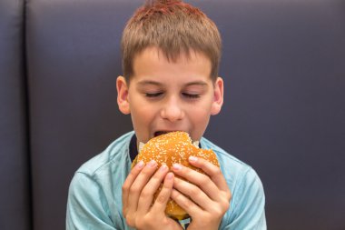 Sevimli çocuk hamburger yiyor