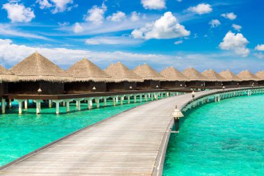 Su Villaları (Bungalovlar) ve yaz günü Maldivler 'deki tropik sahildeki ahşap köprü