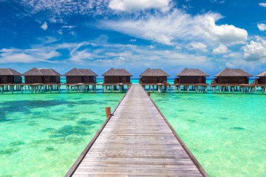 Su Villaları (Bungalovlar) ve yaz günü Maldivler 'deki tropik sahildeki ahşap köprü
