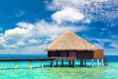 Su Villaları (Bungalovlar) ve yaz günü Maldivler 'deki tropik sahildeki ahşap köprü