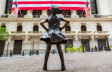 NEW YORK CITY, USA - MARCH 15, 2020:  Fearless Girl Statue looking up at  New York Stock Exchange building at Wall Street in Manhattan, New York City, USA clipart