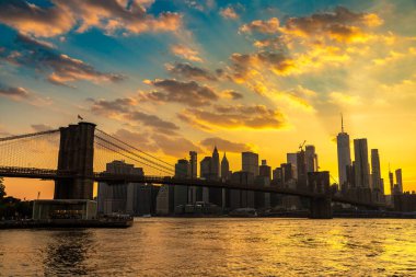 Brooklyn Köprüsü 'nün günbatımı ve New York City, ABD' deki Manhattan şehir merkezinin panoramik manzarası.
