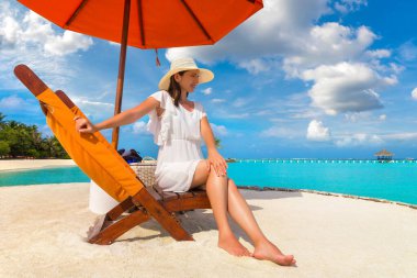 Güneşli bir yaz gününde lüks bir tropik plajda güneşlenen güzel bir kadın.